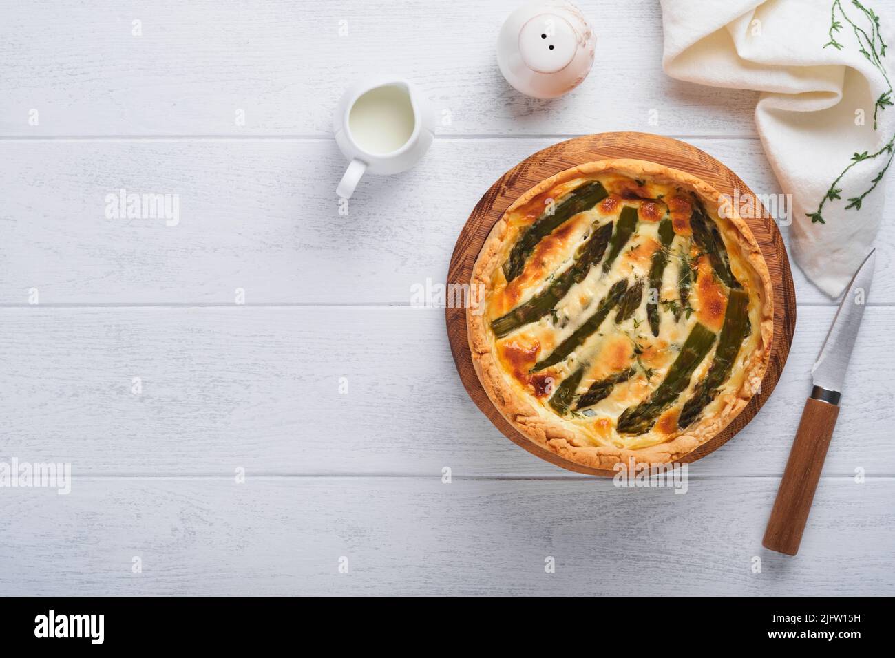 Quiche. Hausgemachte Spargelpastete oder Quiche mit Käse und Spinat auf weißem Holztisch Hintergrund. Traditionelles Französisches Quiche. Draufsicht. Stockfoto