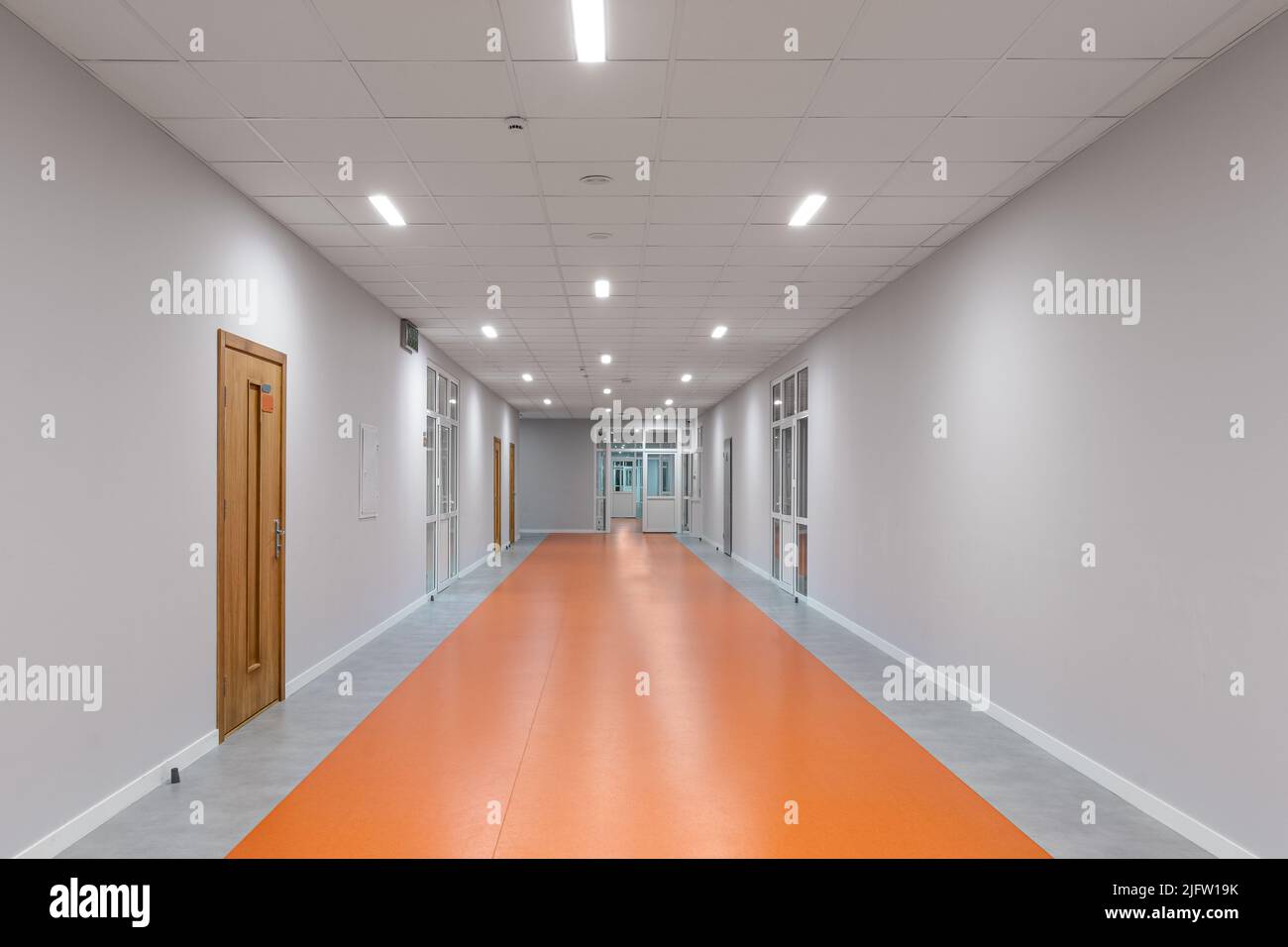 Leerer Schulkorridor. Orangefarbener Boden. Stockfoto