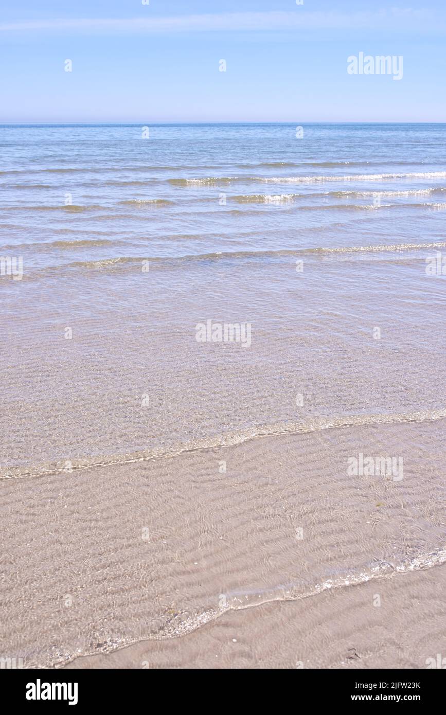 Wunderschöne Strandlandschaft und Horizont unter einem klaren blauen Himmel, Kopierraum. Ruhige und ruhige Meereslandschaft mit dem Meer bei Ebbe an einem sonnigen Tag Stockfoto