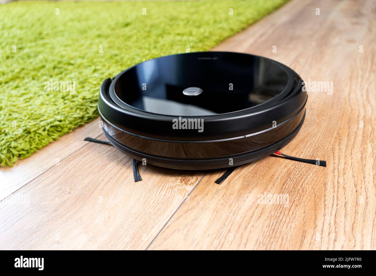 Automatischer Roboter-Staubsauger in Schwarz auf einem grünen Teppich. Neue  moderne Technologien für die Reinigung von Wohnungen. Smart Home  elektronischer Assistent Stockfotografie - Alamy