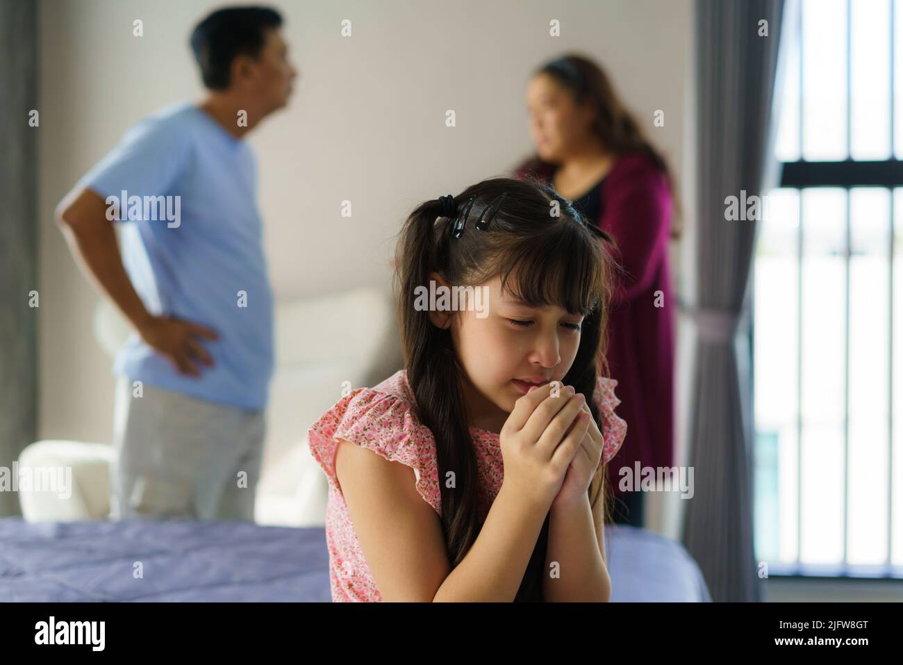 Familiengewalt und Familienkonflikt Konzept, trauriges kleines Mädchen mit Unschärfe der Mutter kämpfen Vater mit Streit zu Hause. Stockfoto