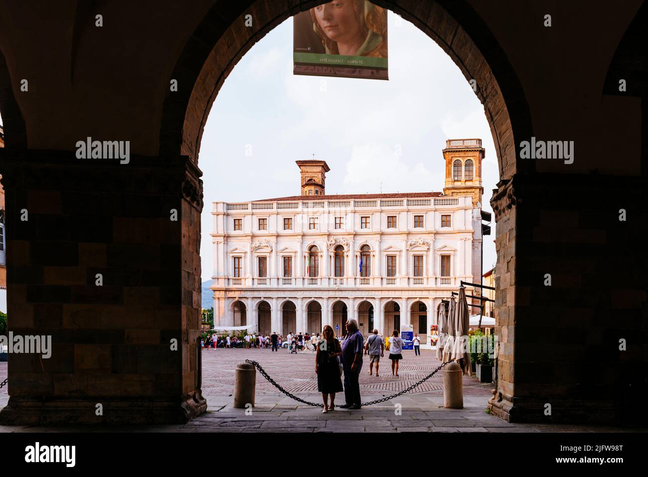 Die Biblioteca civica Angelo Mai durch die Bögen des Erdgeschosses des Palazzo della Ragione gesehen. Piazza Vecchia, Bergamo, Lombardei, Italien, E Stockfoto