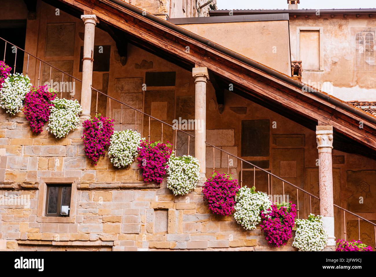 Detail der Treppe zum Aufstieg auf den Glockenturm, geschmückt mit Blumen. Der Bürgerturm - Torre Civica, bekannt unter dem Namen Campanone, ist ein historischer Mo Stockfoto