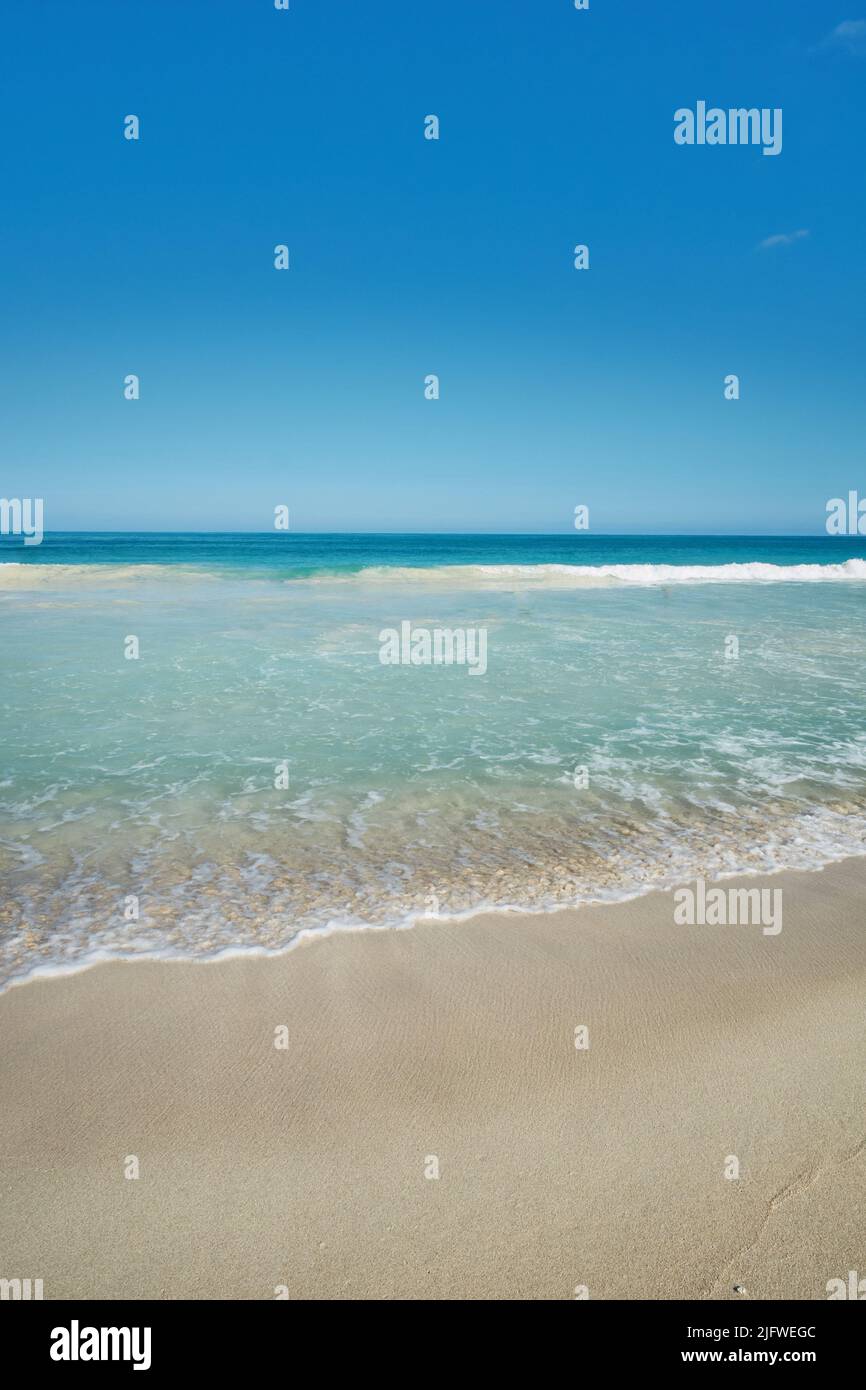In einem tropischen Resort mit klarem, blauem Himmel und Copyspace werden Ozeanwellen an eine leere Strandküste gespült. Ruhige und friedliche Landschaft im Sommer zu genießen Stockfoto