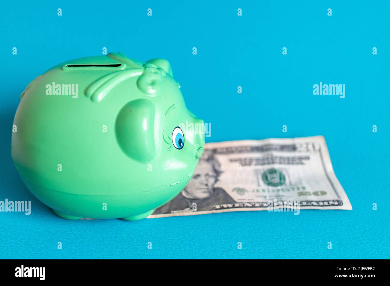 Sparschwein mit Dollarschein auf blauem Hintergrund, finaziales Krisenkonzept Stockfoto