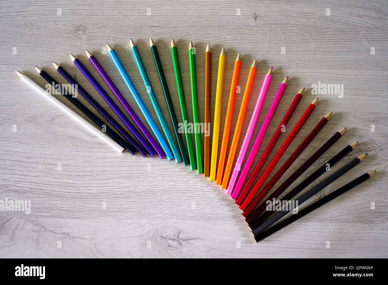 Ein Tisch voller farbiger Schulstifte, die einen Regenbogen bilden, und Vorräte für Schulkinder Stockfoto