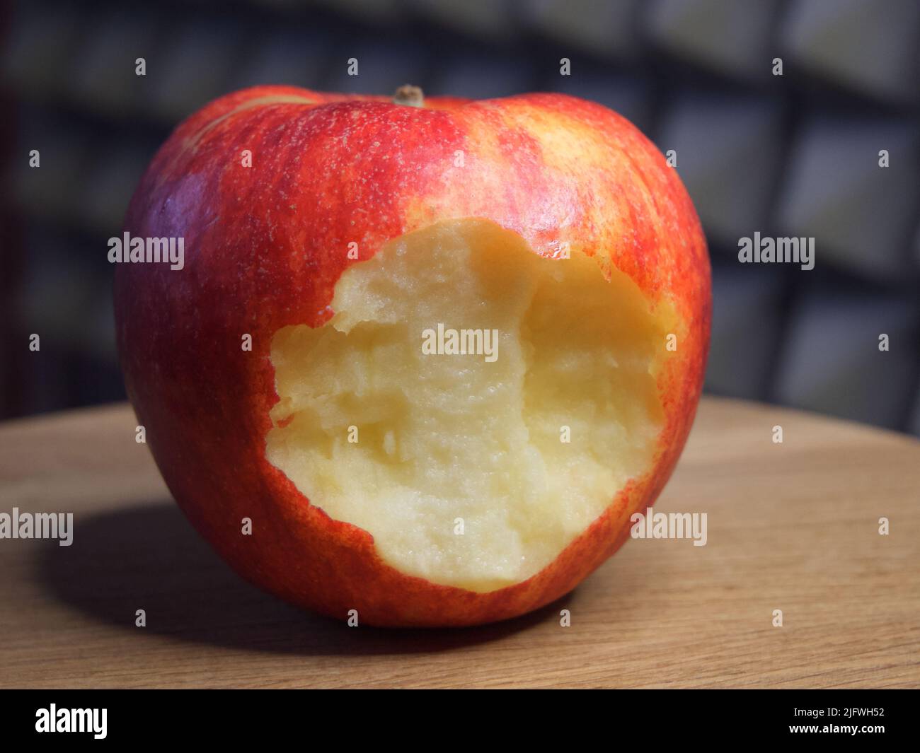 Ein gebissenen roten Apfel auf einer hölzernen Oberfläche. Reifer Apfel Stockfoto