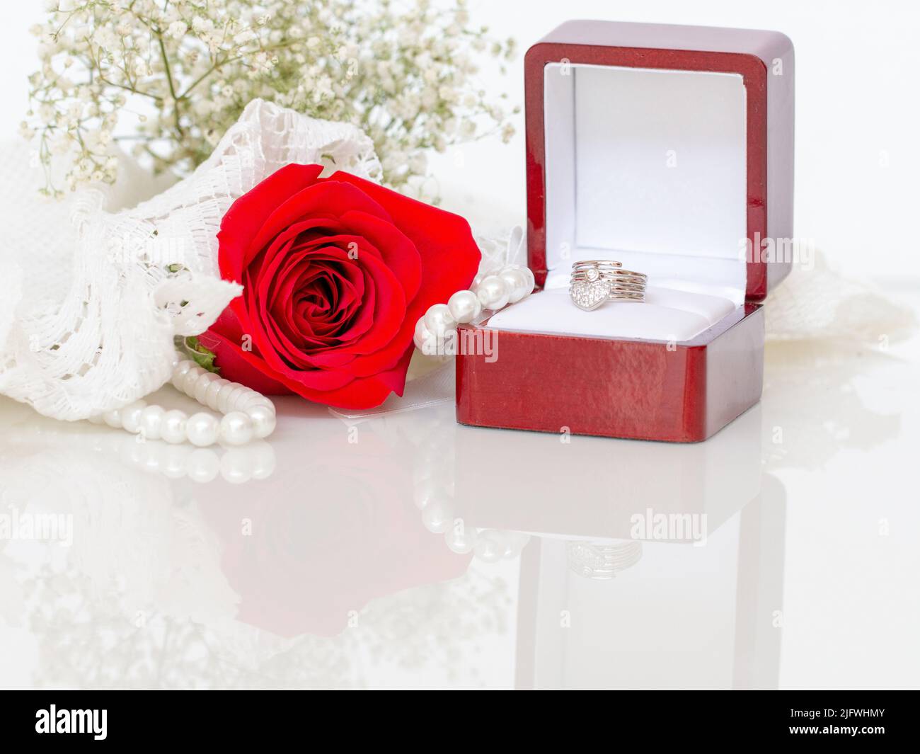 Rote Rose und Dimond Ring auf dem Glastisch für eine Braut. Stockfoto
