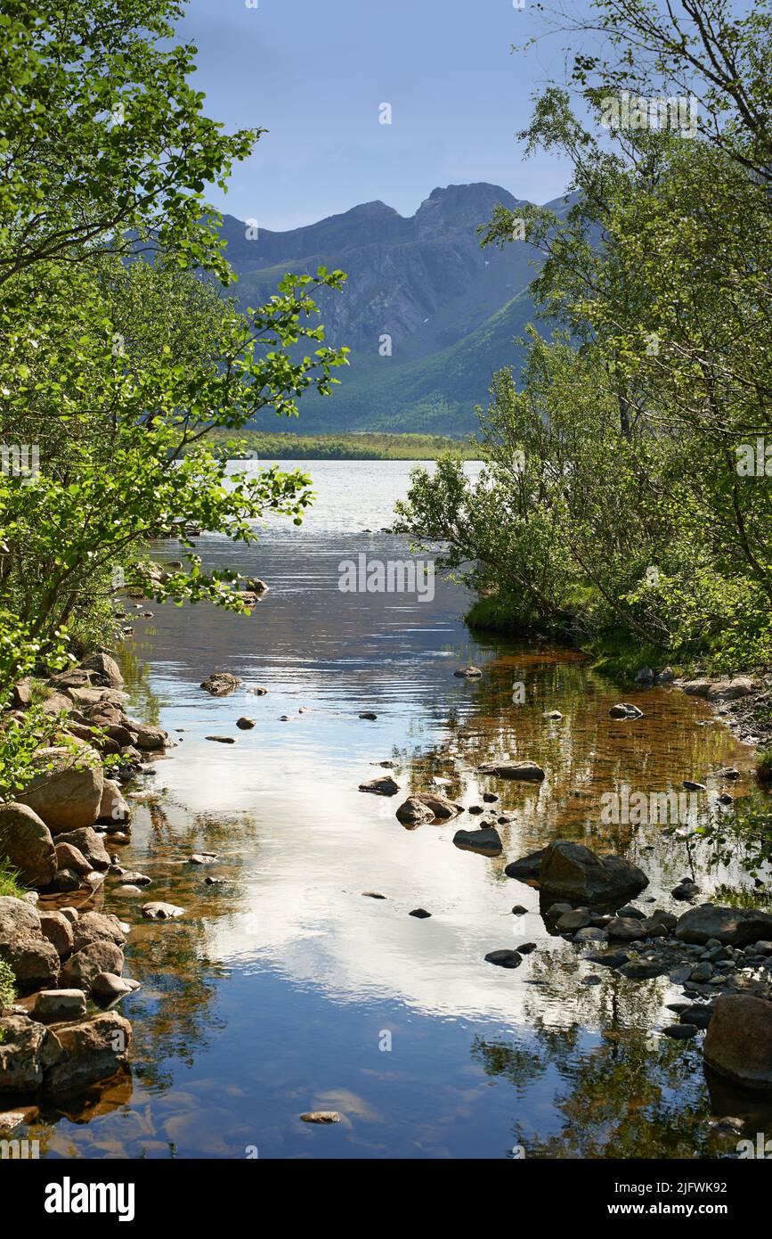 Landschaft von See und Fluss nördlich des polaren und arktischen Kreises in Norland. Berge und Hügel in abgelegener Gegend mit felsigem Bach in Bodo, Norwegen Stockfoto