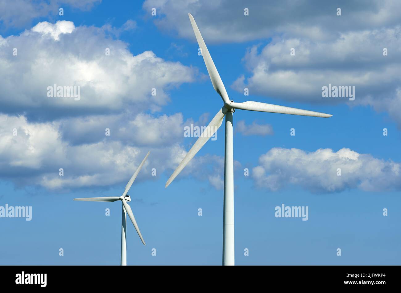 Windturbinen und Umweltinfrastruktur isoliert gegen blauen Himmel mit Kopierfläche auf leerem Energiepark. Propeller verwandeln sich nachhaltig Stockfoto