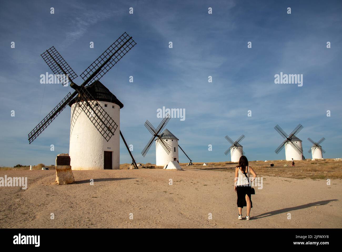 Una joven tomando una foto con el móvil de un molino en el cerro molinos de viento de Campo de Criptana, España Stockfoto