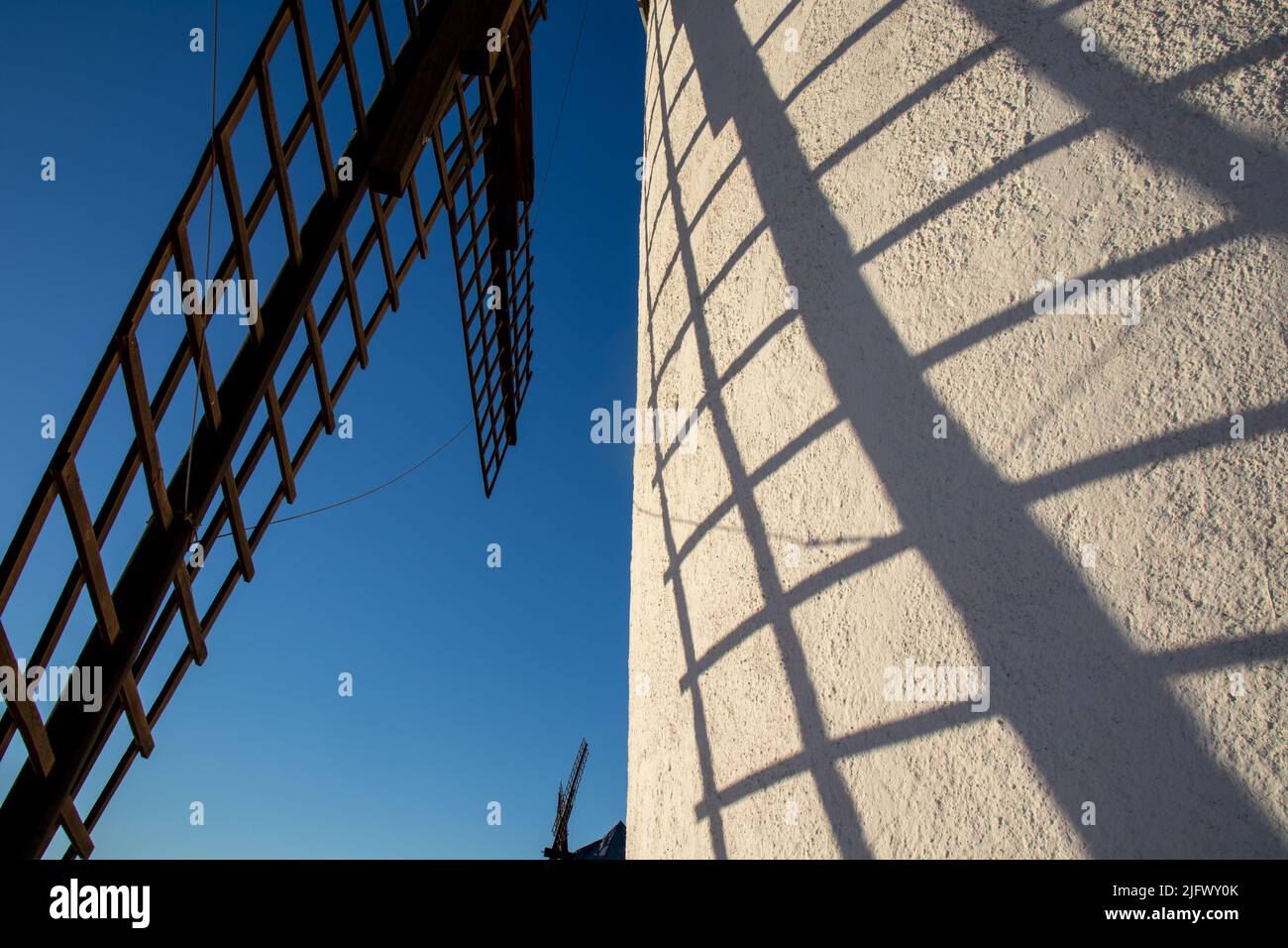 Primer plano de las aspas de un molino de viento y su sombra en el molino, cielo azul, Campo de Criptana, España Stockfoto