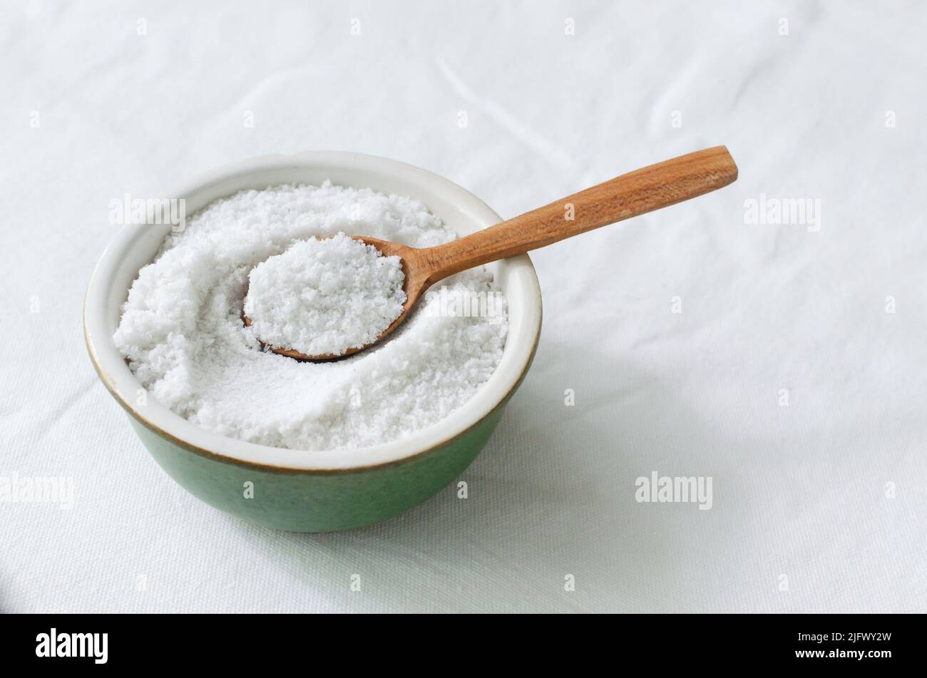 Feines Salz in einer Keramikschale mit einem Holzlöffel auf dem Tisch. Rustikaler Stil. Natürliche Ressource. Horizontale Ausrichtung. Speicherplatz kopieren. Stockfoto