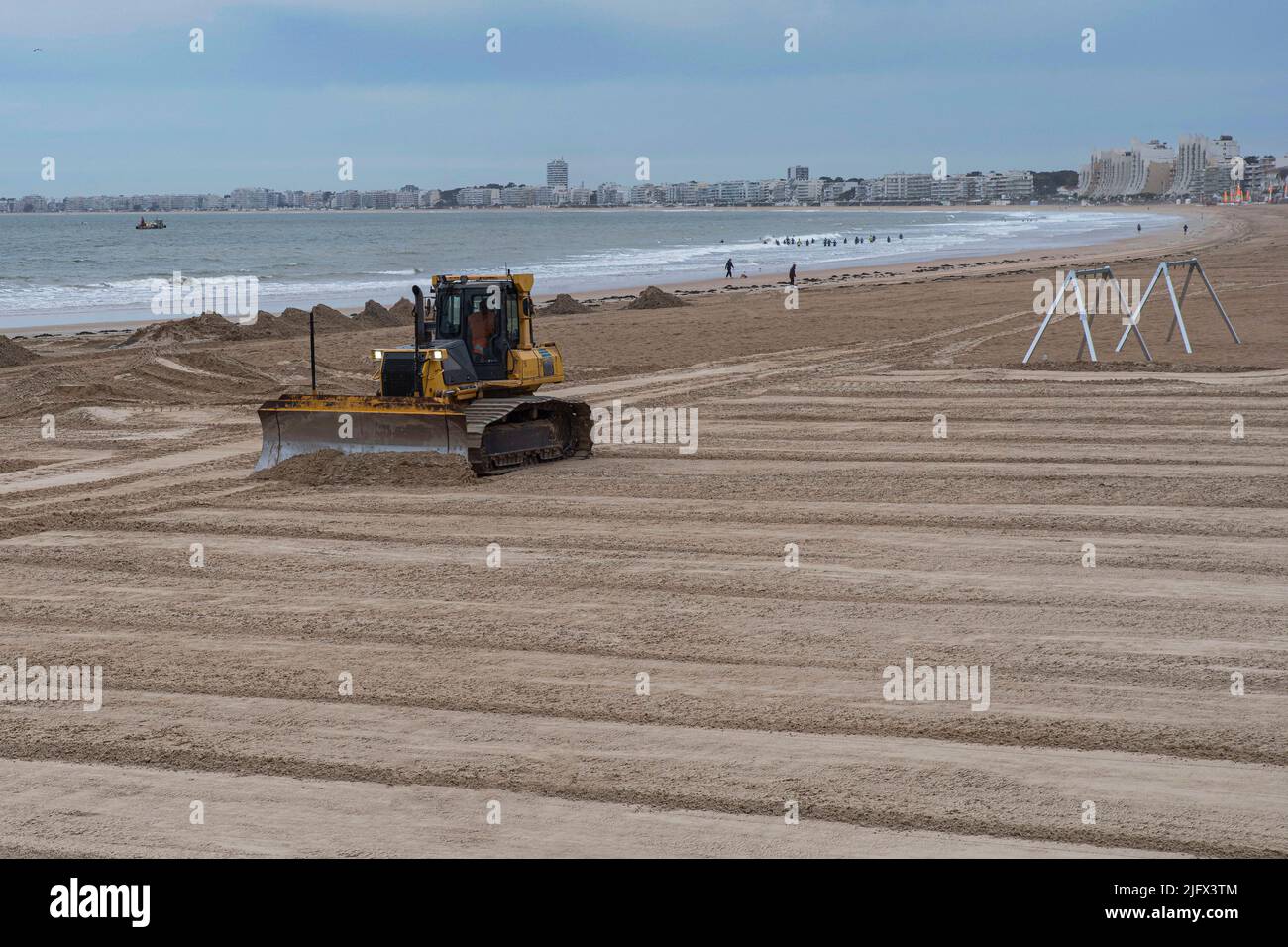 Eine Planierraupe bewegt Sand an einem Strand, um ihn zu gleichen und zu pflegen Stockfoto