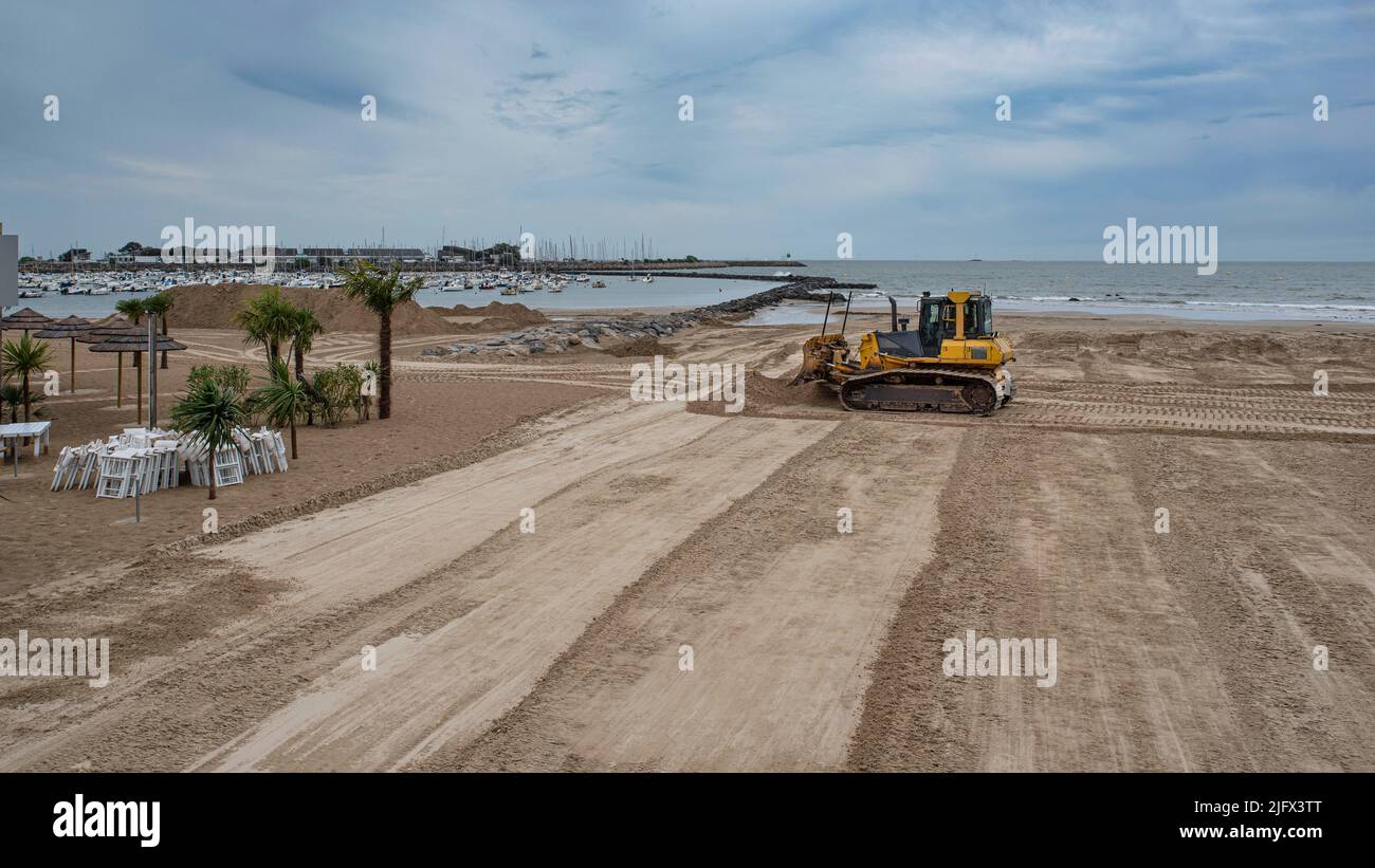 Eine Planierraupe bewegt Sand an einem Strand, um ihn zu gleichen und zu pflegen Stockfoto