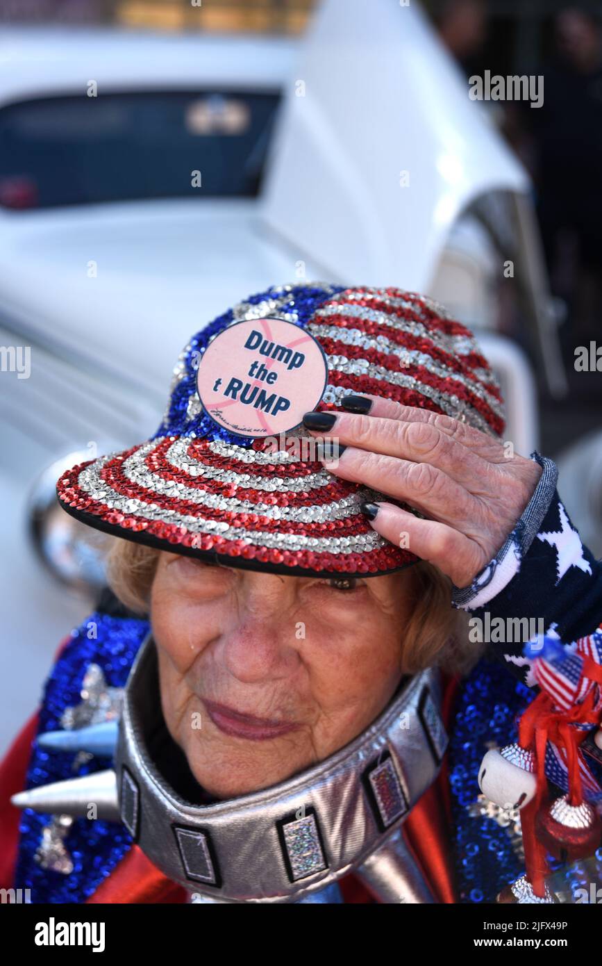 Eine in patriotischen Rot-, Weiß- und Blautönen gekleidete Frau trägt bei einer Veranstaltung am 4. Juli in Santa Fe, New Mexico, einen Knopf „Dump the Trump“ auf ihrem Hut. Stockfoto