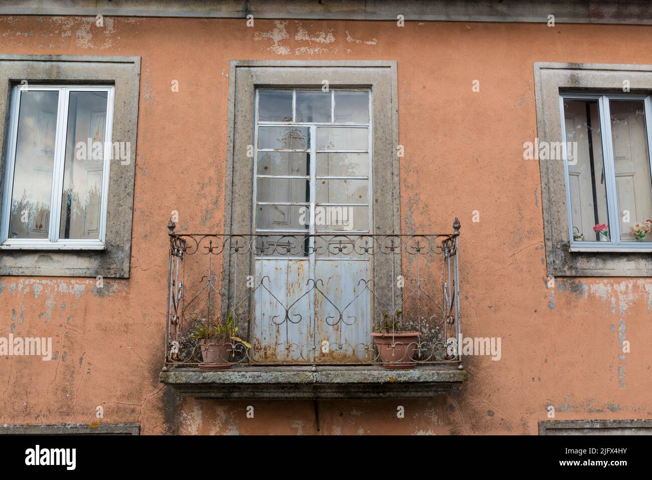 Fassade eines orangefarbenen schäbigen Hauses im Dorf Sao Paio. Gouveia, Portugal Stockfoto
