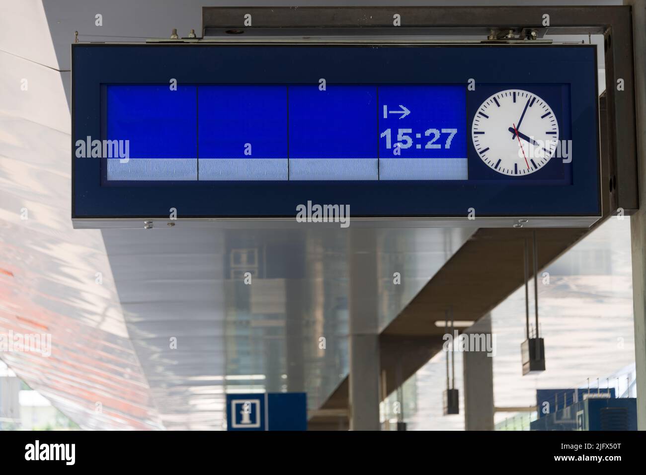 Bahnhofsdisplay mit analoger Uhr und moderner silberner Metallarchitektur in unscharfem Hintergrund als Konzept für Zugfahrten Zugansagen a Stockfoto