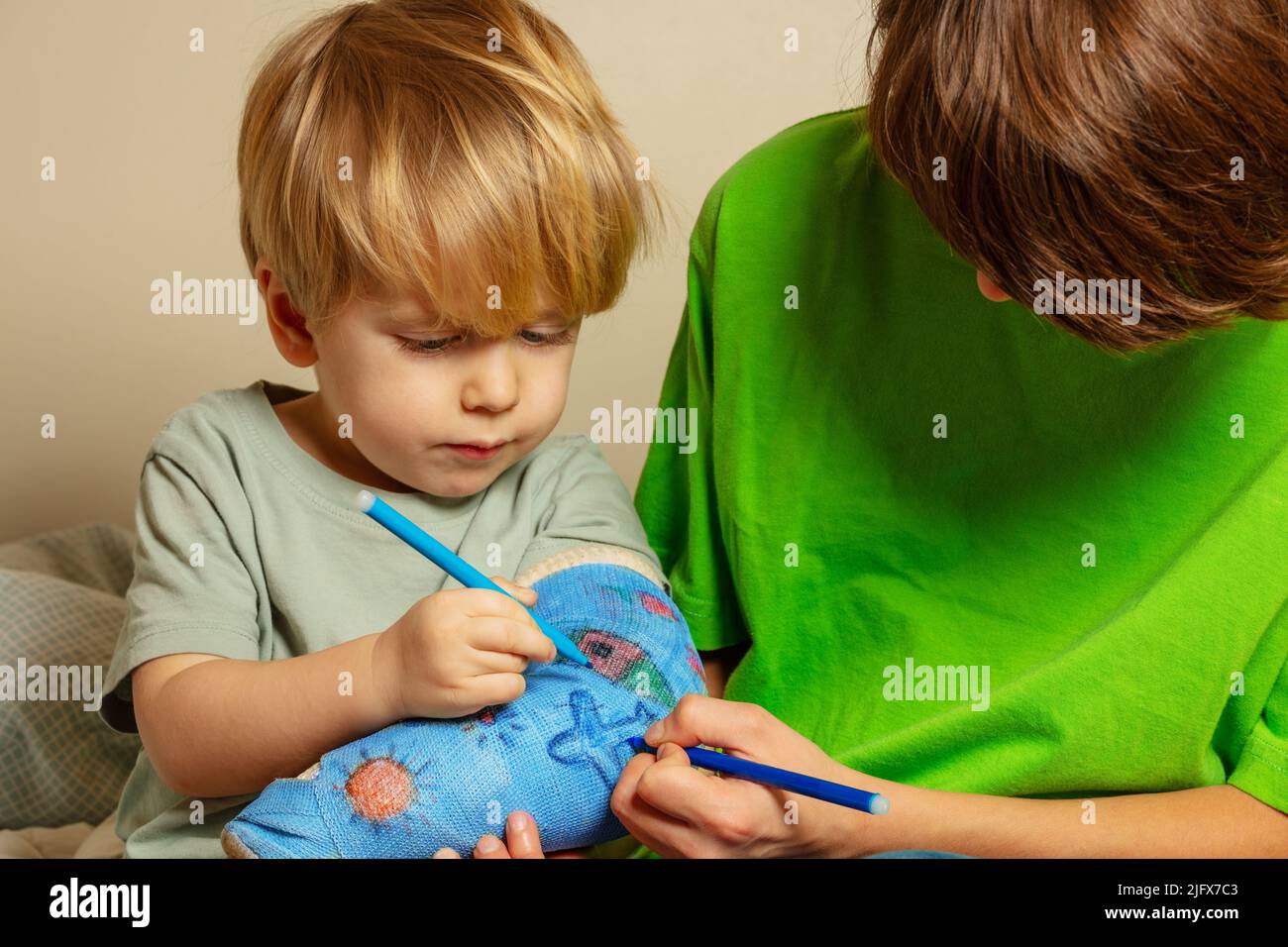 Zwei Kinder zeichnen gebrochenen Handputz mit kindlichen Zeichnungen Stockfoto Zwei Kinder zeichnen gebrochenen Handputz mit kindlichen Zeichnungen Stockfoto