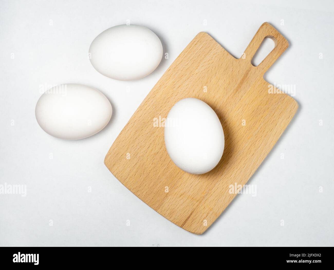 Eier auf einem Schneidebrett auf weißem Hintergrund. Ungeschälte Eier. In Shell. Vor dem Kochen Stockfoto