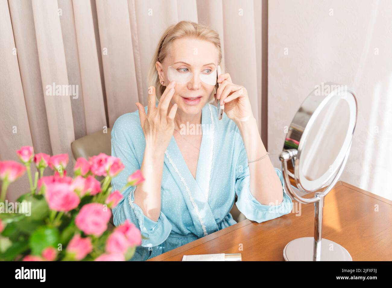 Eine reife Frau mit Augenmaske telefoniert zu Hause. Stockfoto