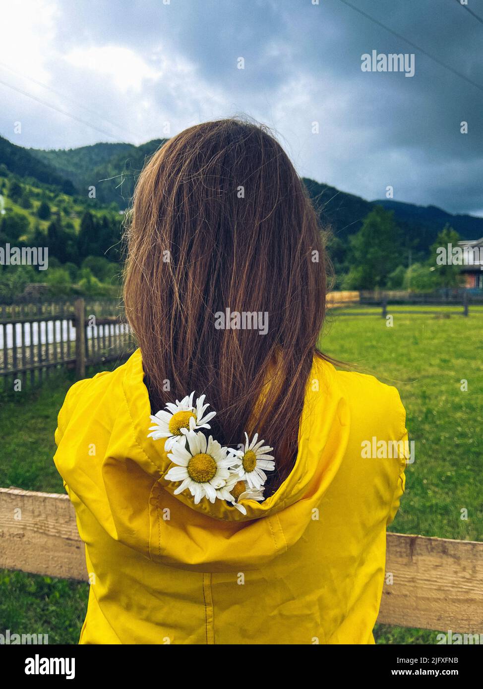 Blumen im Haar eines Mädchens im gelben Regenmantel Stockfoto