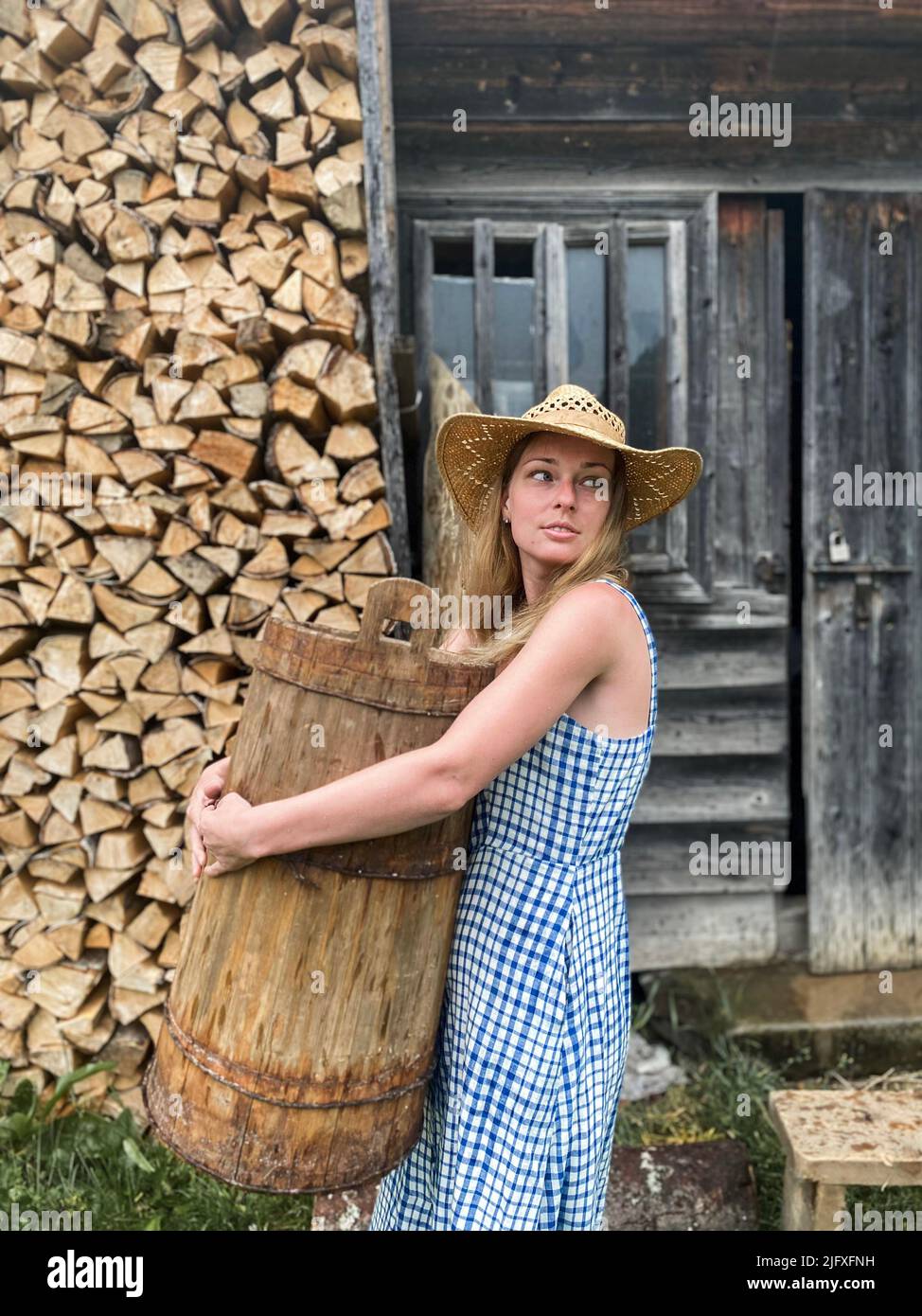 Ein schönes Mädchen trägt einen hölzernen Eimer im Dorf. Stockfoto