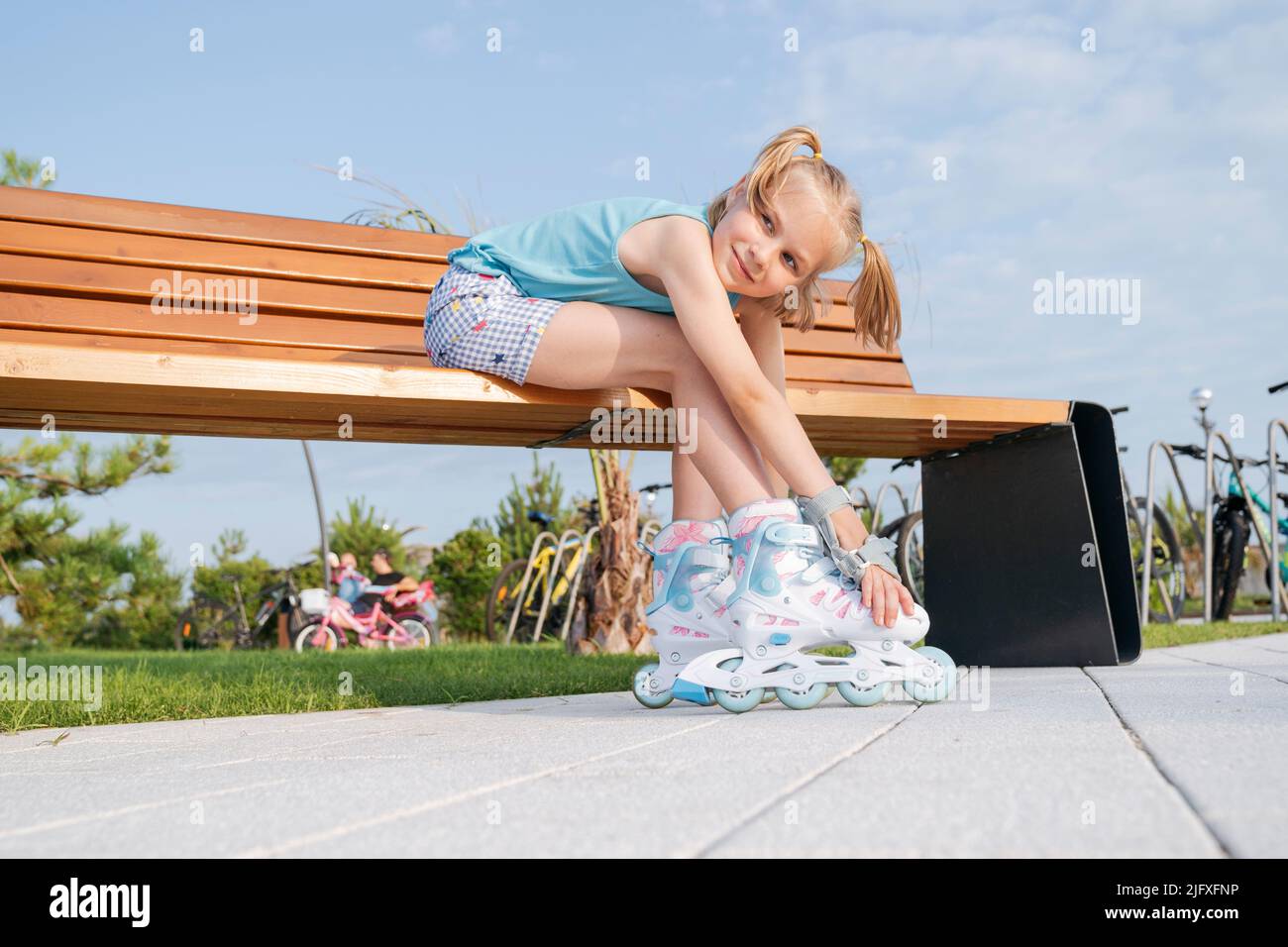 Ein Mädchen in Rollschuhe sitzt auf einer Parkbank. Stockfoto