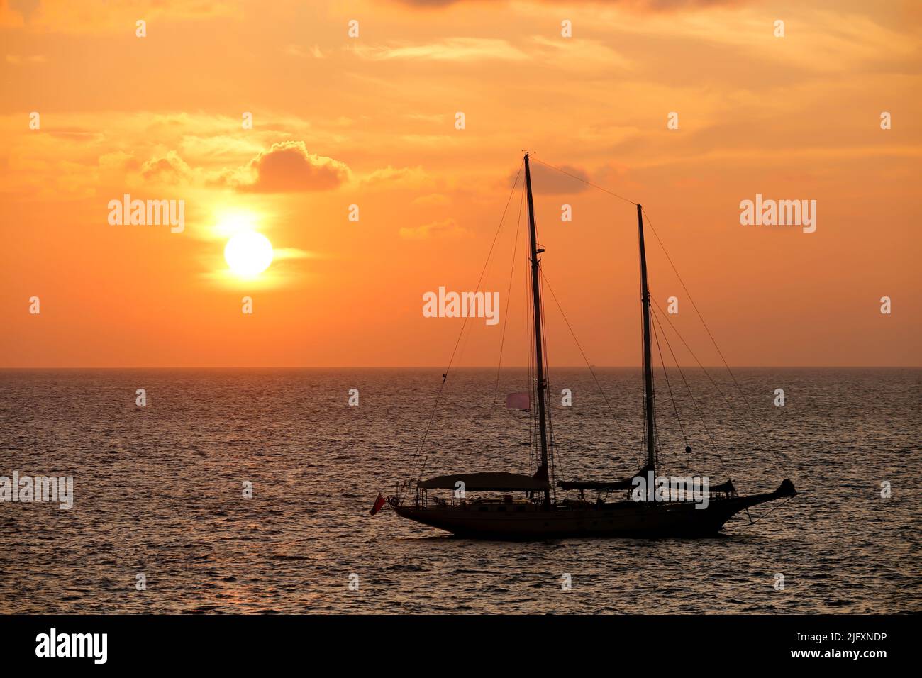 Schoner Segelboot bei Sonnenuntergang mit Horizont über dem Wasser auf Phuket, Thailand. Stockfoto