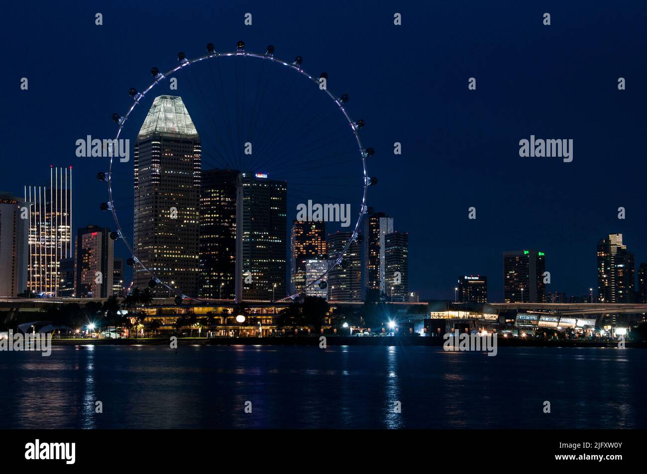Downtown Singapore bei Nacht, mit dem Singapore Flyer Beobachtungsrad im Vordergrund Stockfoto