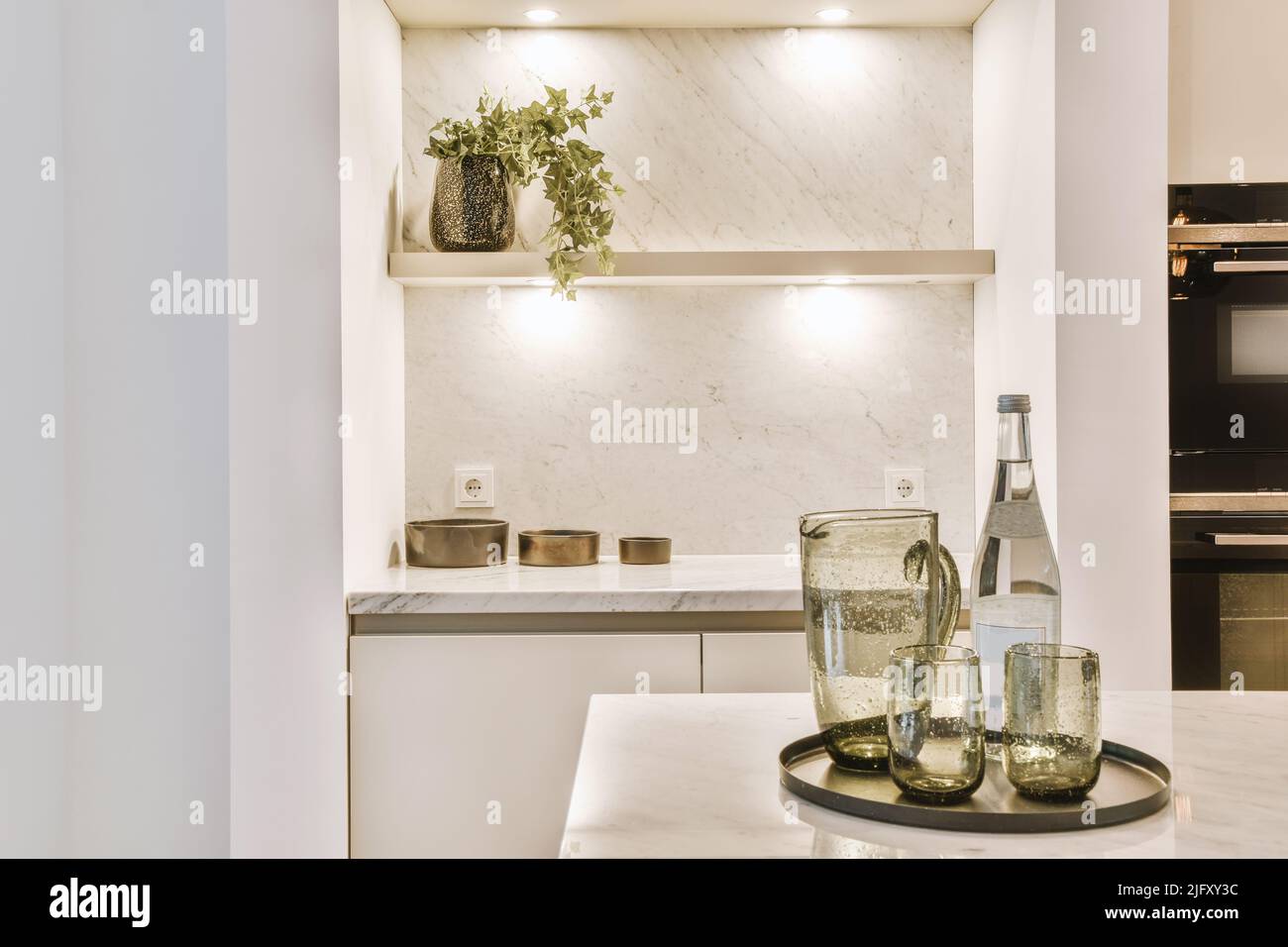 Regale, Krug, Flasche und Gläser auf einem Tablett auf einem offenen Küchentisch auf einem Tablett auf einem offenen Küchentisch Stockfoto