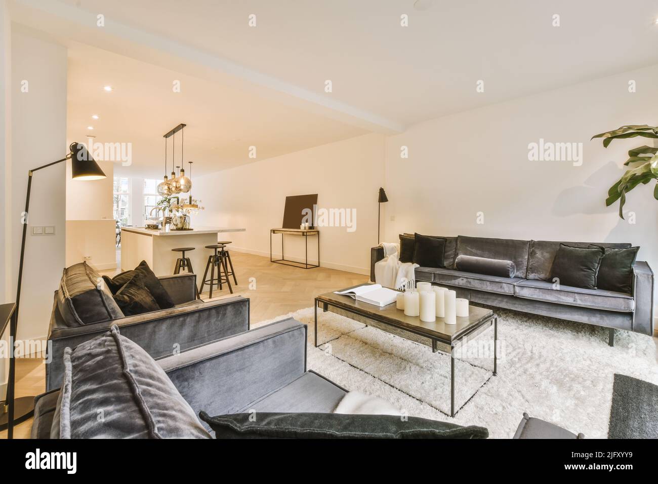 Loungebereich mit Sofa und Küche mit Pendelleuchten in geräumigen Zimmern eines modernen Apartments Stockfoto