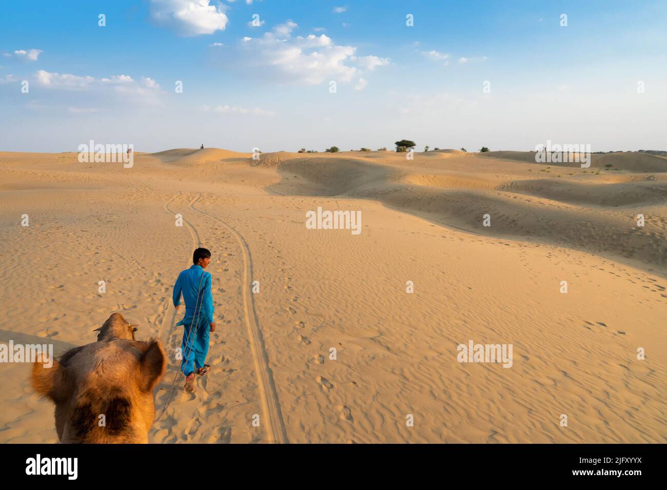 Thar-Wüste,Rajasthan,Indien-15. October 2019 : Kamelführer eines Kamels, Camelus dromedarius, in Sanddünen. Aussichtspunkt für Touristen, auf dem Kamel sitzend. Stockfoto