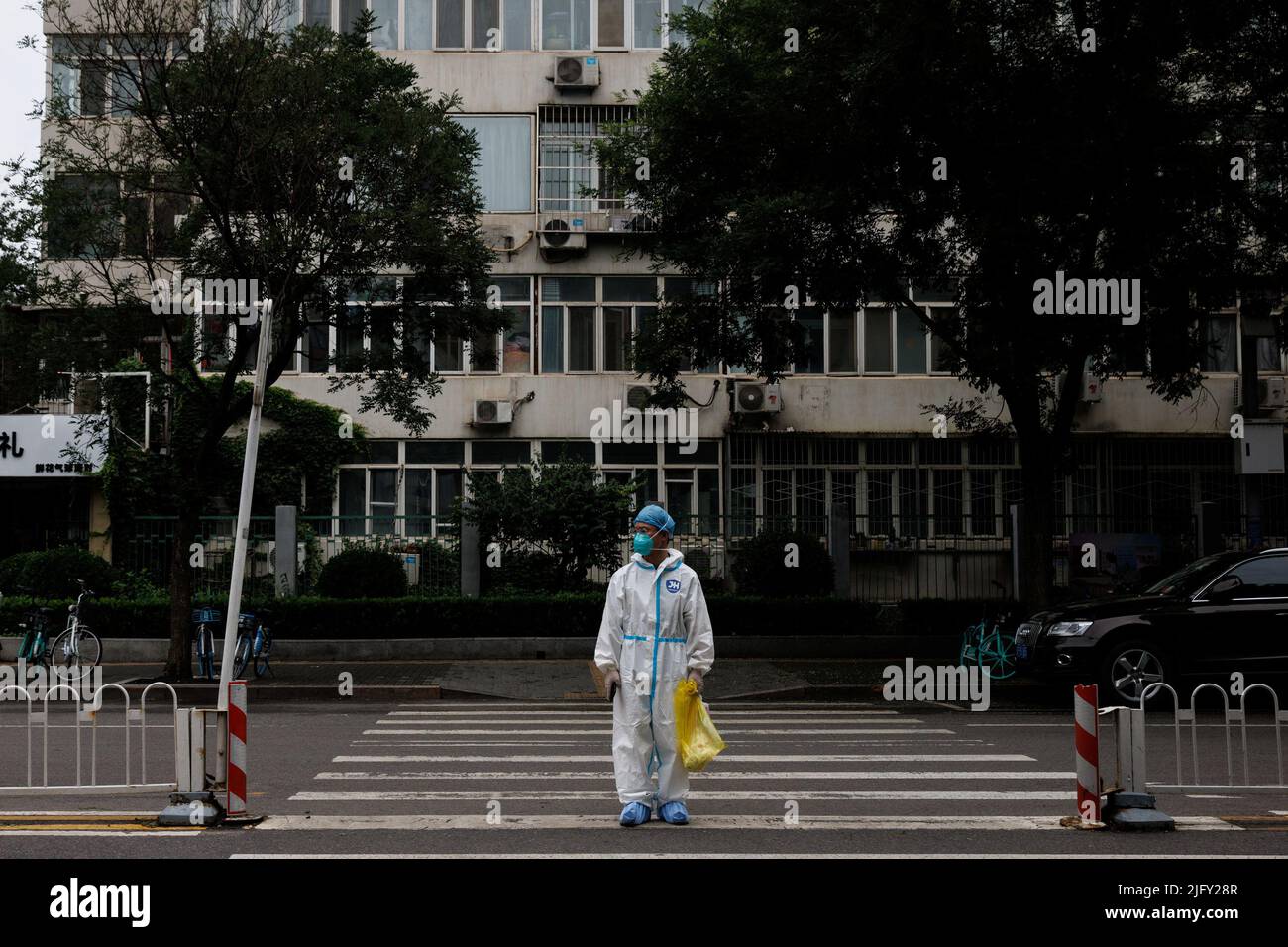 Medizinisches Personal in einem Schutzanzug überquert eine Straße nach einem Ausbruch der Coronavirus-Krankheit (COVID-19) in Peking, China, 6. Juli 2022. REUTERS/Thomas Peter Stockfoto