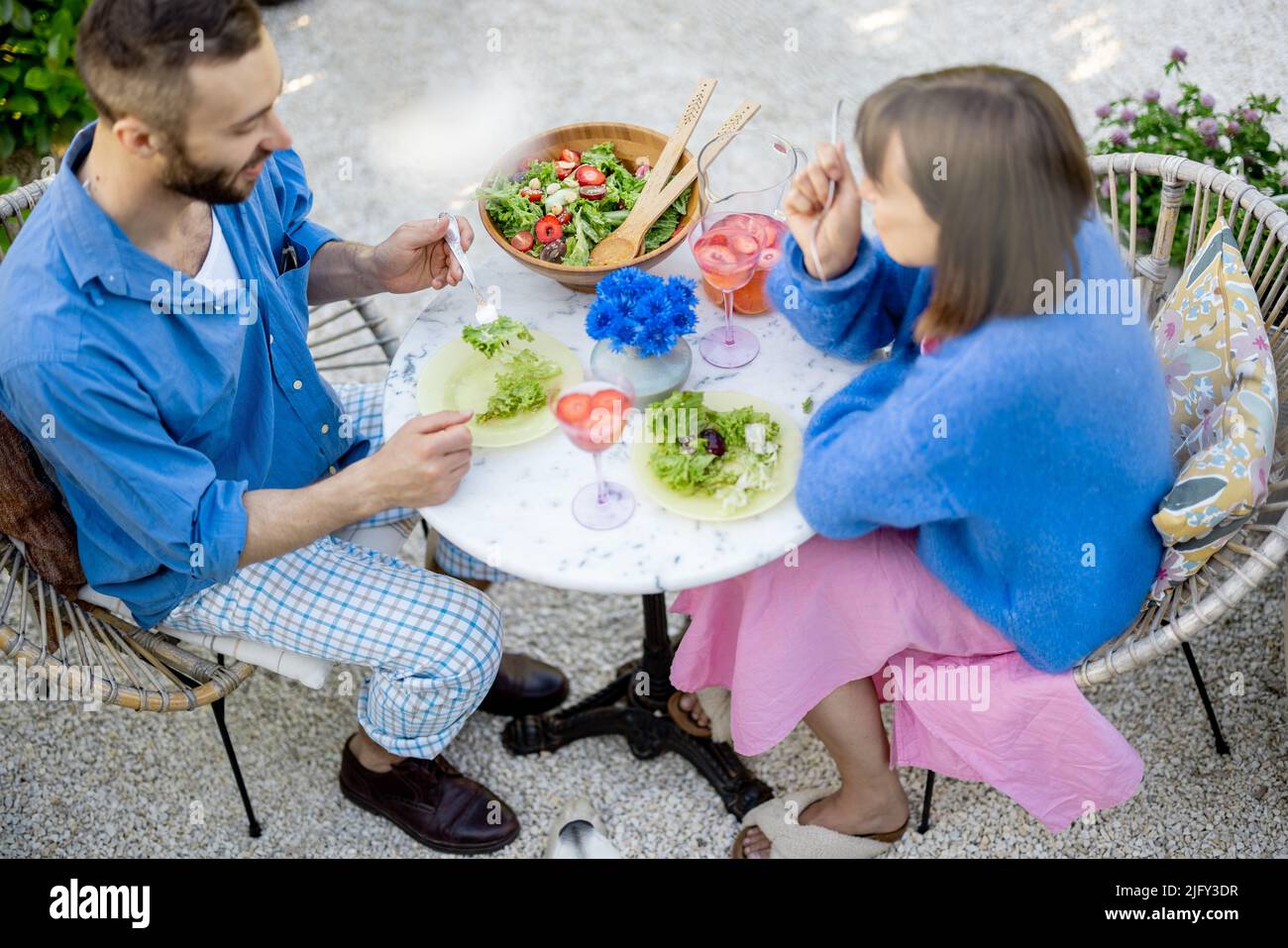 Junge Männer und Frauen essen zu Mittag mit gesundem Salat und trinken draußen Stockfoto