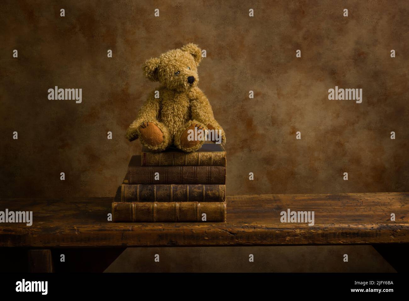 Entzückender kleiner Teddybär auf einem Stapel alter Bücher auf einem rustikalen alten Holzregal. Dies ist für digitales Compositing geeignet. Stockfoto