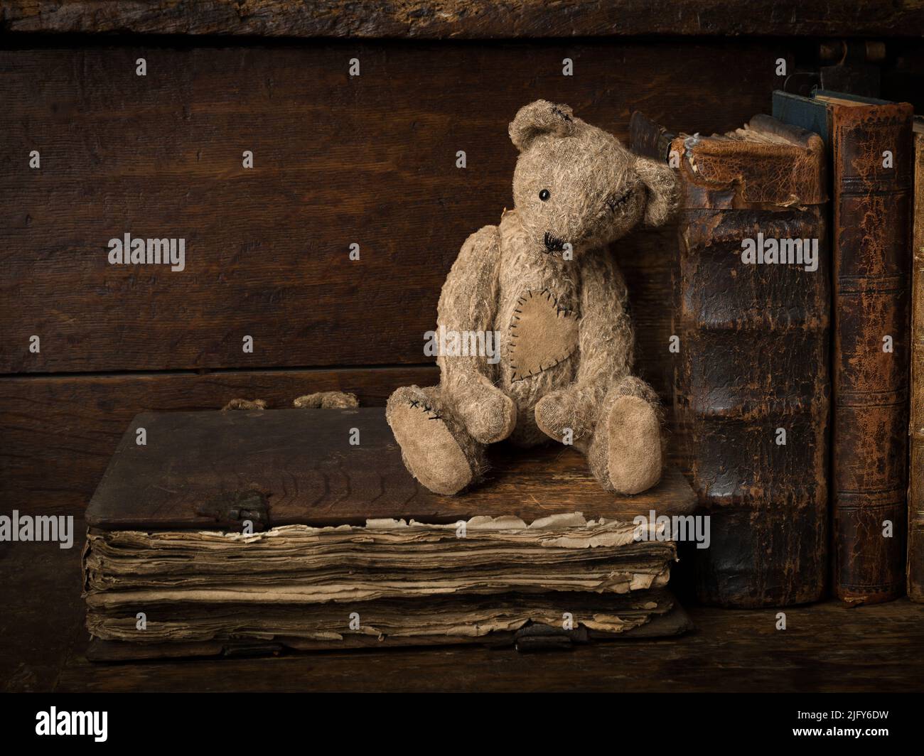 Gestapelte antike Bücher und ein Teddybär auf einem rustikalen alten Holzregal. Dies ist für digitales Compositing geeignet. Stockfoto