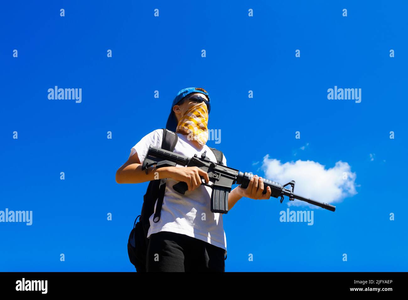 Junger Zivilist mit einem automatischen Gewehr. Schussaufnahmen, Waffenkontrollkonzept. Stockfoto