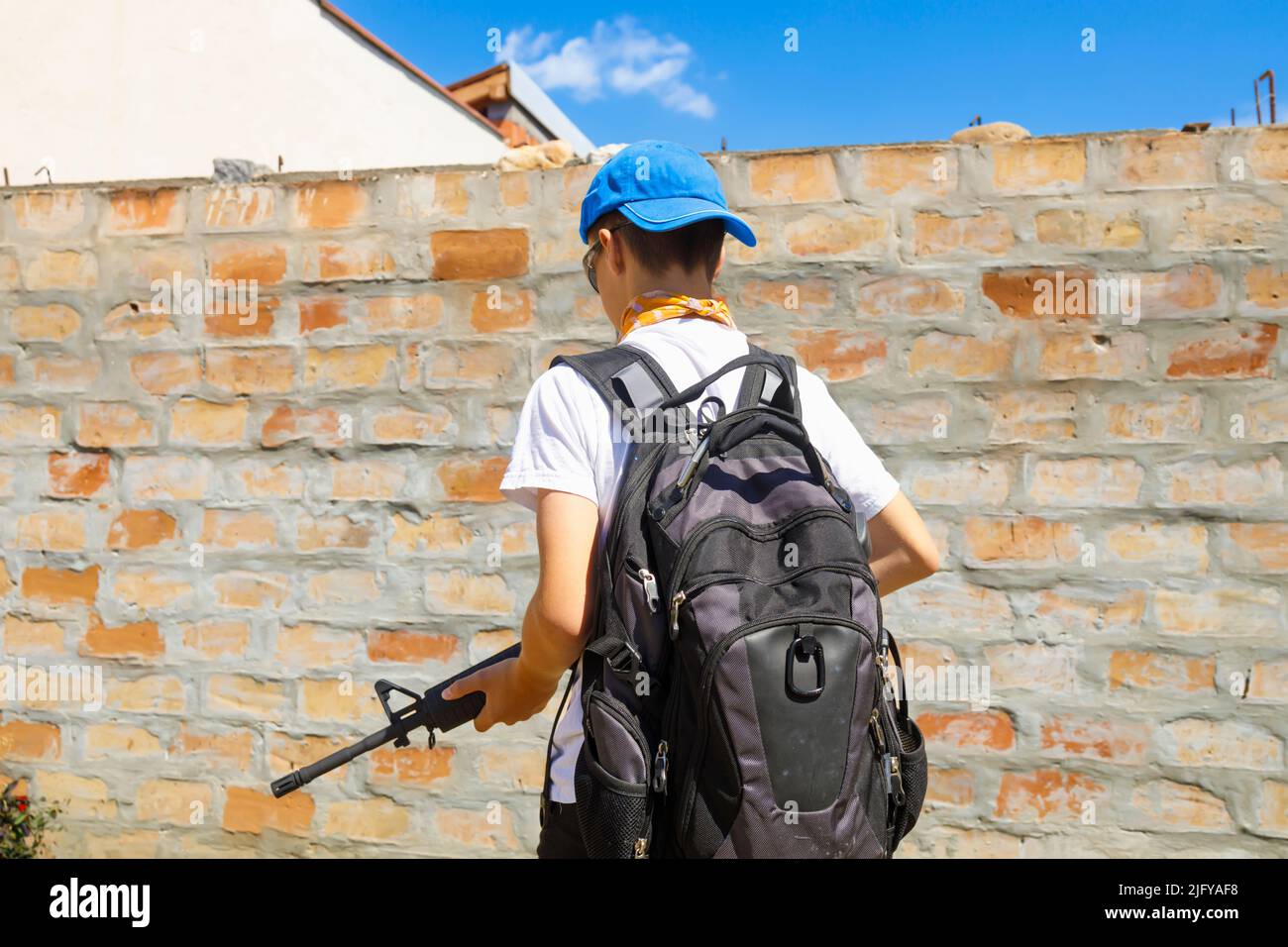 Yong Mann zu Fuß mit einem automatischen Gewehr-Gun-Steuerung, Schule Schießereien Konzept. Stockfoto