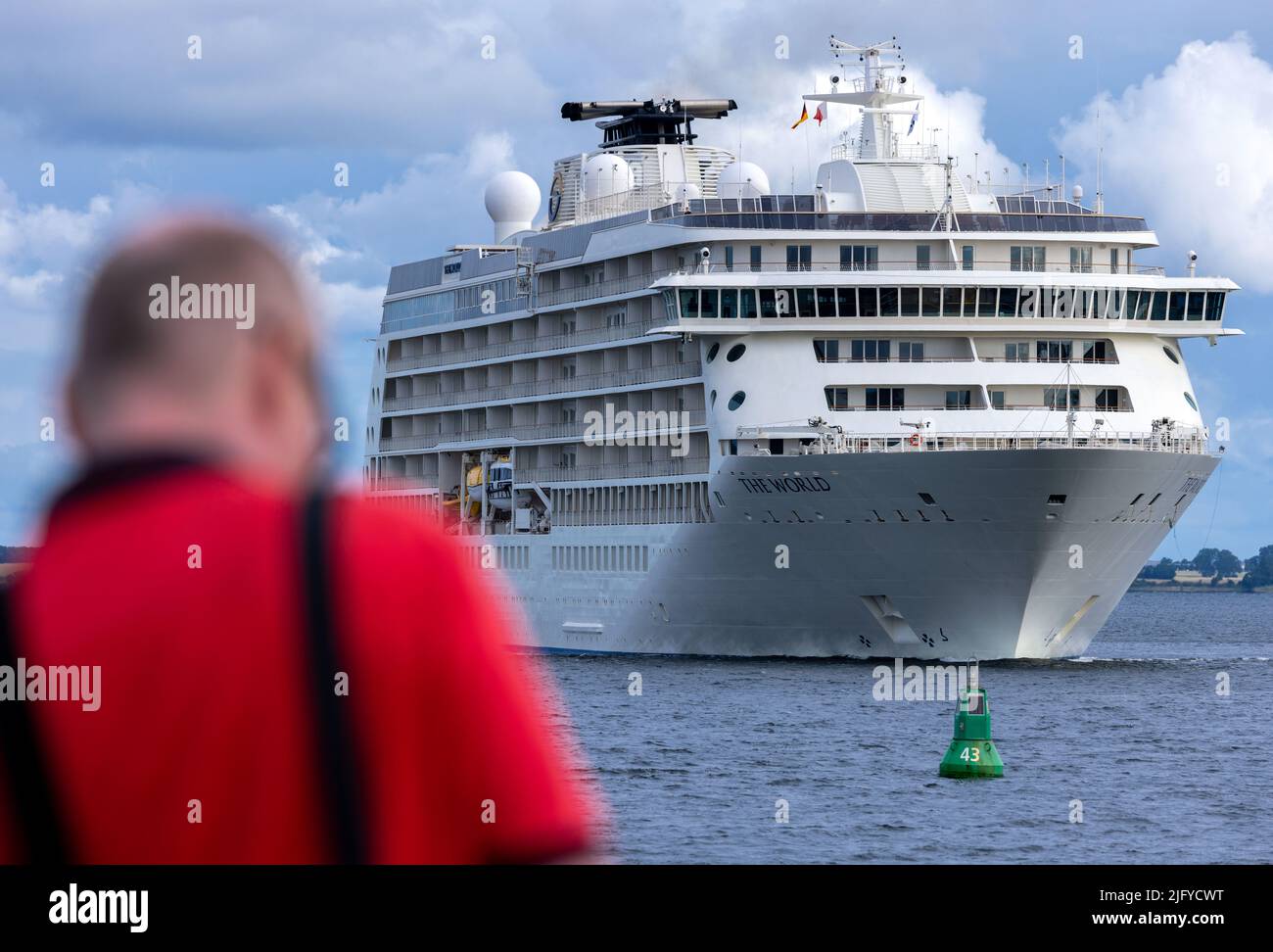 Wismar, Deutschland. 06.. Juli 2022. Ein Mann fotografiert den Luxusliner „The World“, der am Morgen vom Pier aus in den Hafen einfährt. Auf dem 196 Meter langen Schiff leben mehr als 100 Familien aus 20 Nationen in ihren Privatwohnungen und reisen gemeinsam um die Welt. Quelle: Jens Büttner/dpa/Alamy Live News Stockfoto