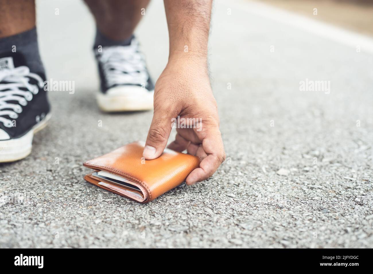 Asian Mann verlieren braune Brieftasche auf der Straße in Touristenattraktion. Konzept zum Verlust von Geldbörsen. Konzentrieren Sie sich auf den Geldbeutel Stockfoto