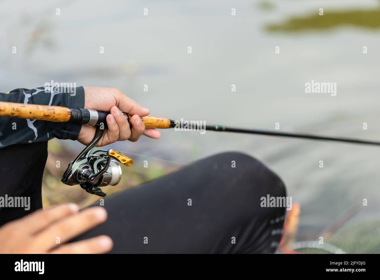 Nahaufnahme Angelrolle und Angelrute in Fischerhand in einem Teich Stockfoto