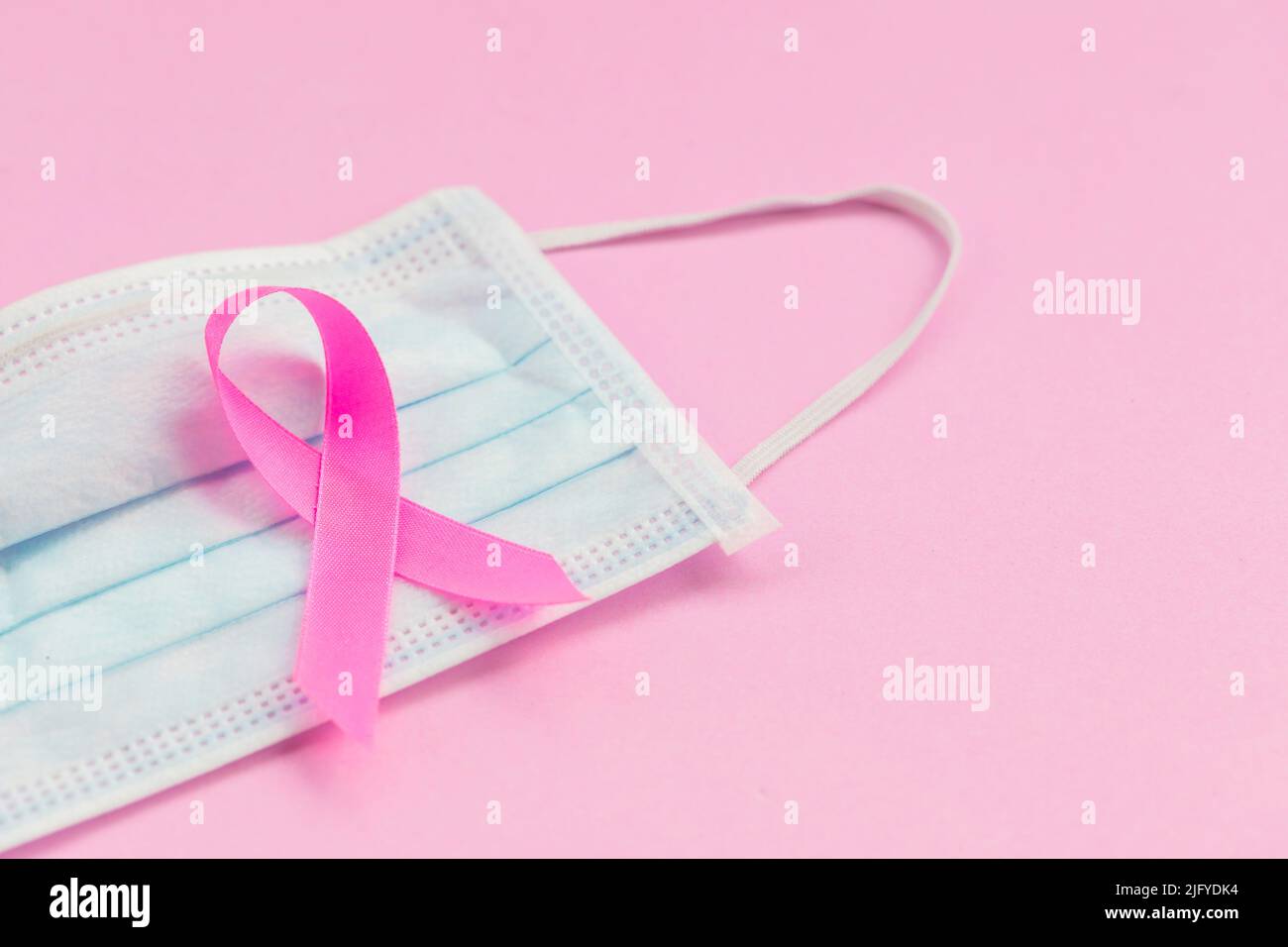 Brustkrebskonzept : Draufsicht rosa Band und Schutzmaske Symbol der Brustkrebs-Kampagne auf rosa Hintergrund Stockfoto