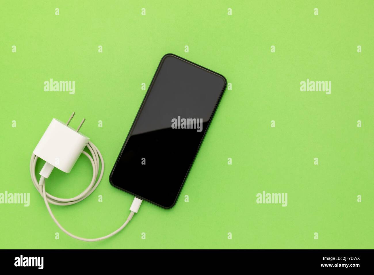 Neues Smartphone von oben mit weißem Ladegerät auf farbigem Hintergrund mit Platz für Text oder Design Stockfoto