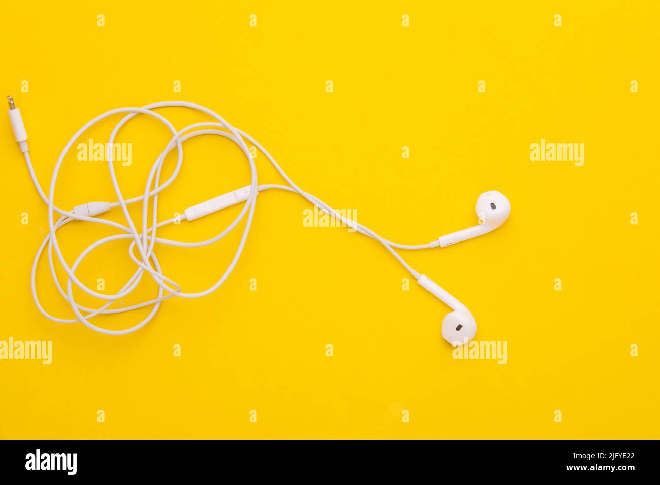 Weißer Ohrhörer aus der Draufsicht auf gelbem Hintergrund. Platz für Text oder Design kopieren Stockfoto