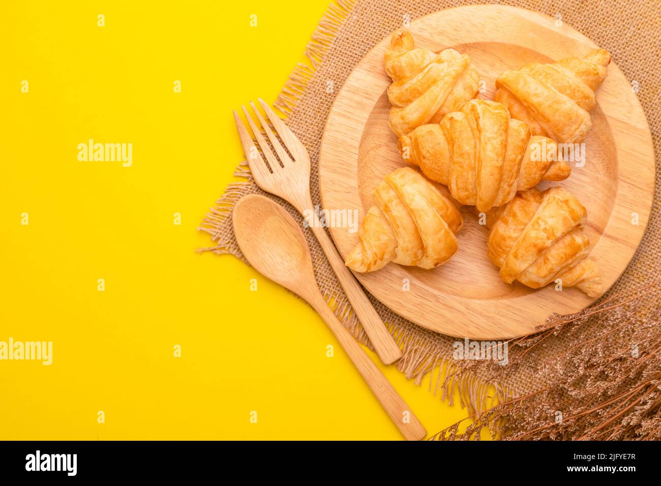 Draufsicht Mini Croissant in Holzschale auf gelbem Hintergrund. Food-Konzept mit Kopierraum Stockfoto