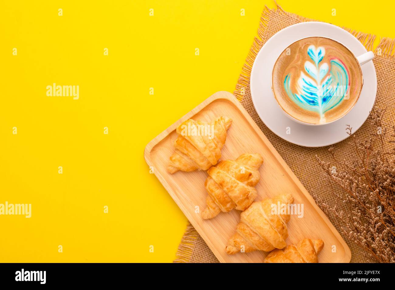 Draufsicht Mini Croissant in Holzschale und Kaffee auf gelbem Hintergrund. Food-Konzept mit Kopierraum Stockfoto