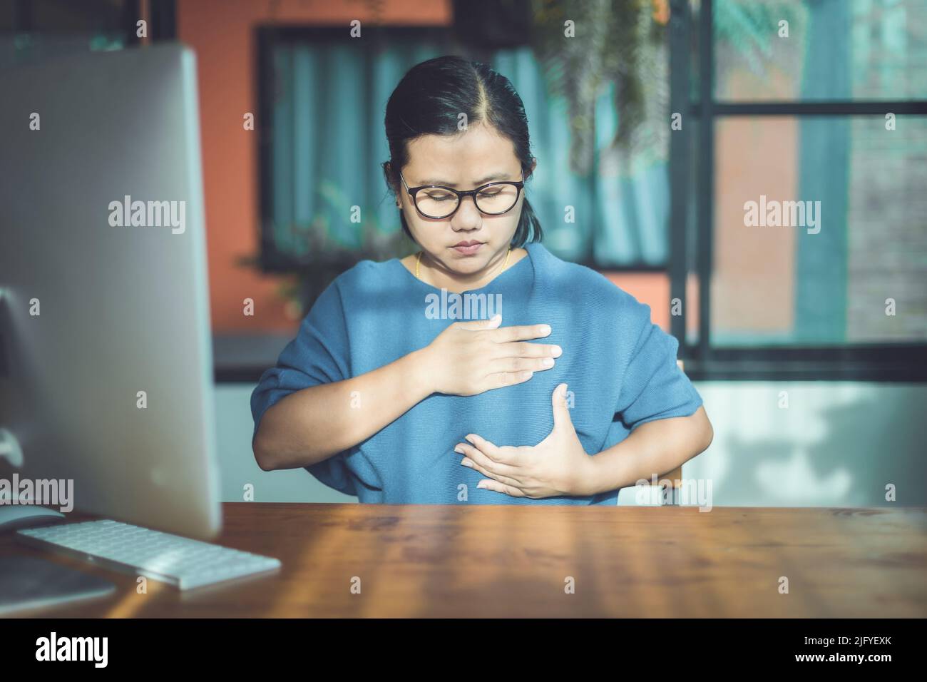 Brustkrebs-Konzept: Asiatische Frau, die Computerbildschirm zum Lernen über das Überprüfen der Brust durch selbst schaut Stockfoto