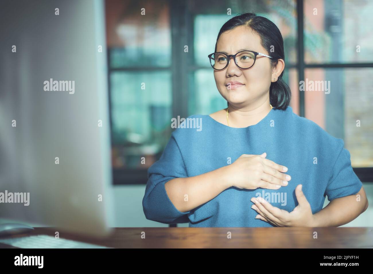 Brustkrebs-Konzept: Asiatische Frau, die Computerbildschirm zum Lernen über das Überprüfen der Brust durch selbst schaut Stockfoto