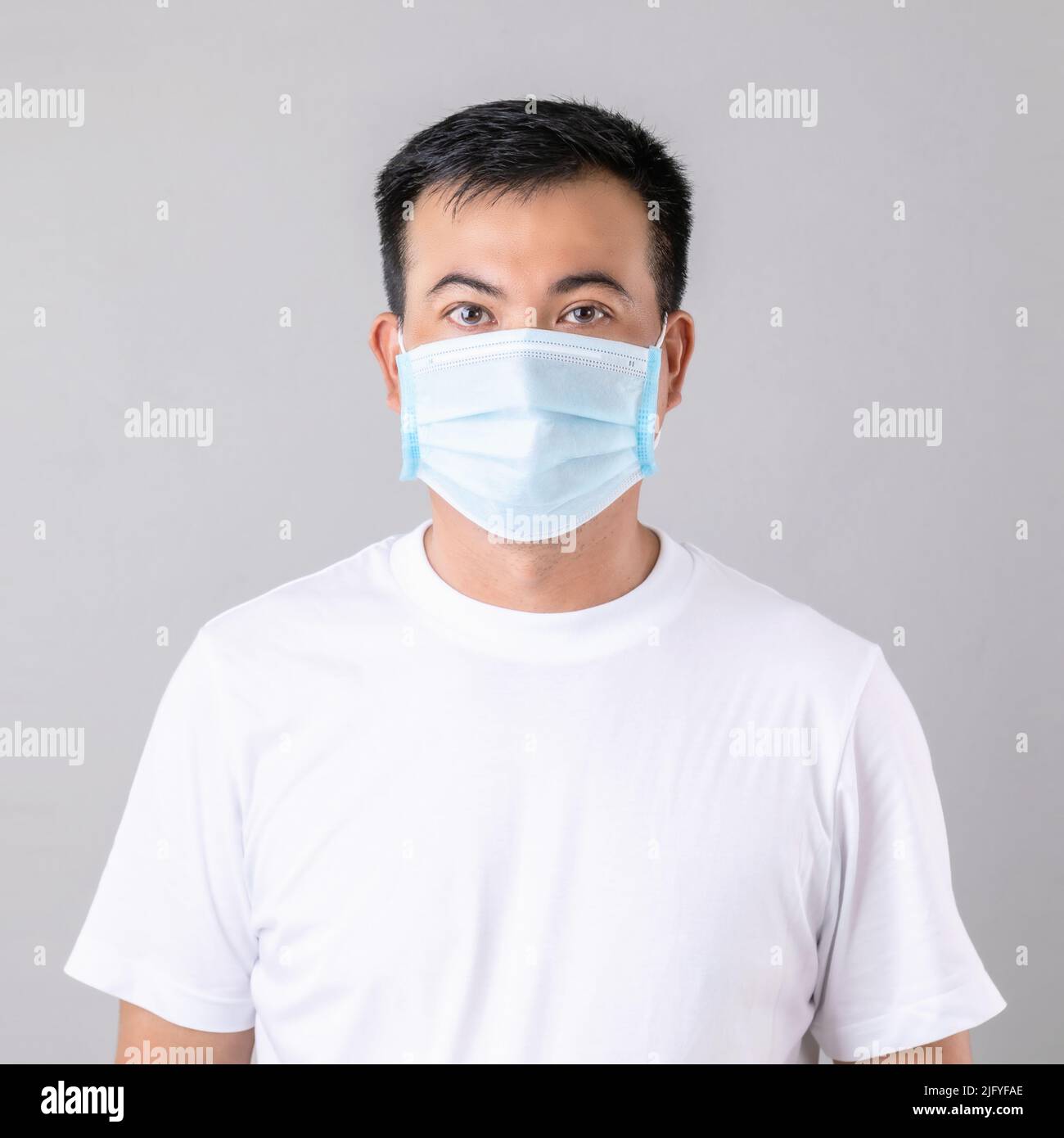 Porträt eines thailändischen Mannes trägt eine schützende Gesichtsmaske, um zu verhindern, dass Virus Studio auf grauem Hintergrund geschossen Stockfoto